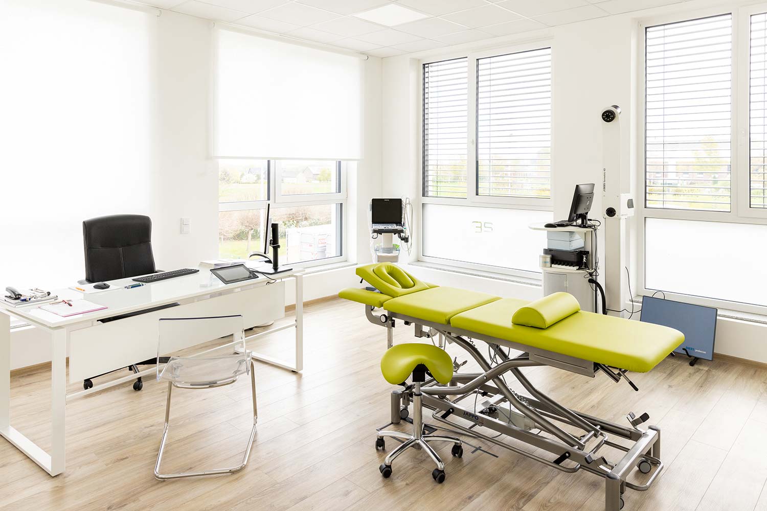 Jan Mende Osteopathie Praxis in Unna. Ansicht eines Behandlungsraumes mit Schreibtisch, einer Liege und diversen Apparaturen